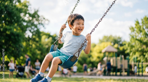 Portrait of a happy young boy laughing and playing on a blue swing at a sunny outdoor playground