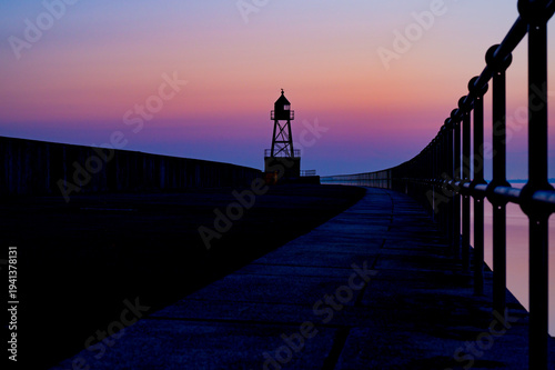 Pier, pier light and railings at sunrise, silhouette creates a tranquil scene, view of the North Sea or Jade Bay in the morning at the cross-range light, Old Pier in 26382 Wilhelmshaven, Germany