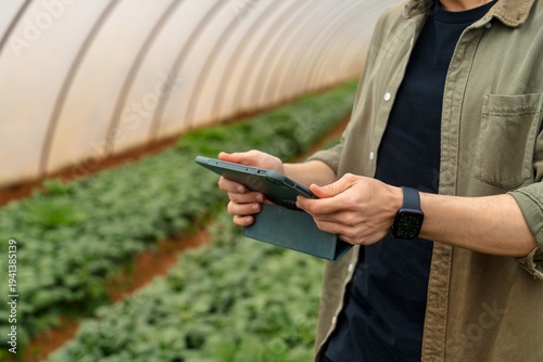 Farmer using tablet for crop monitoring in greenhouse
