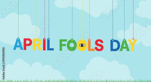 Colorful april fools day sign with marionette strings against a blue sky with fluffy white clouds and green grass