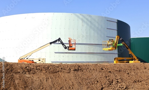 Wallpaper Mural Two aerial platforms working on the construction of a large industrial tank in the oil industry Torontodigital.ca