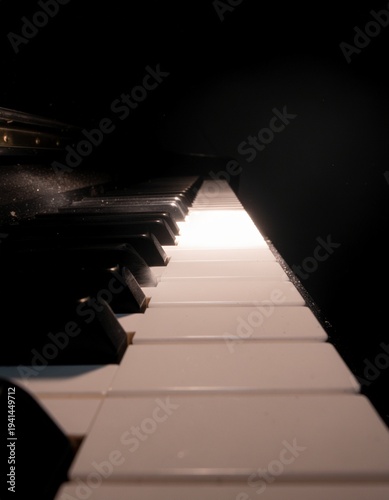 Piano keys illuminated by a beam of light in a dark room close-up