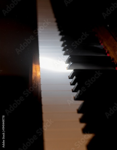 Piano keys silhouetted against bright light from window