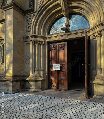 Church is open german text near wooden door