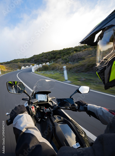 Driver riding motorcycle on empty asphalt road, handlebars view , spring mountains