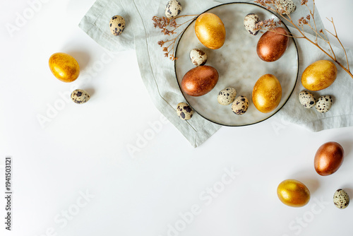 Golden and bronze Easter eggs in a orange plate on a linen napkin on a white background
