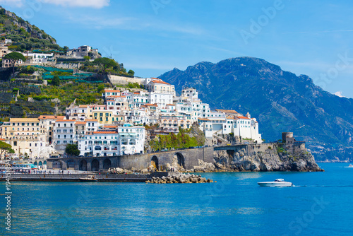Picturesque view of Amalfi, Italy, with charming buildings perched on cliffside, overlooking blue waters of Mediterranean Sea. Amalfi coast is most popular travel and holiday destination in Europe