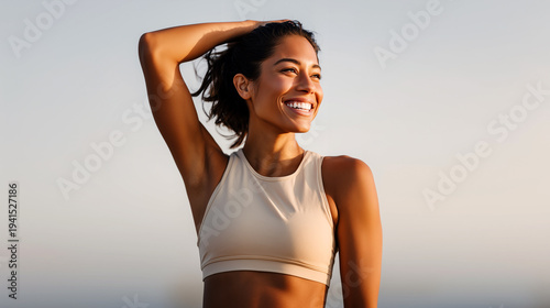 Smiling athletic woman in beige sports bra posing outdoors after workout at golden sunset. Active healthy lifestyle, fitness motivation, energetic female portrait, summer sport, natural background.