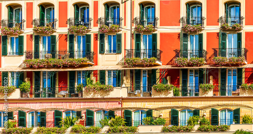 beautiful red and orange hotel facade of house with three green plants and braches and windows in retro italian european style