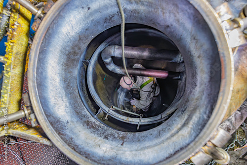 Top view male climbs down the stairs into the tank grease chemical area, confined space safety sling
