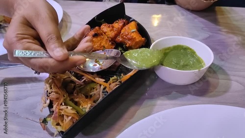 cropped video of female hand serving green chutney with a spoon during dinner in a restaurant