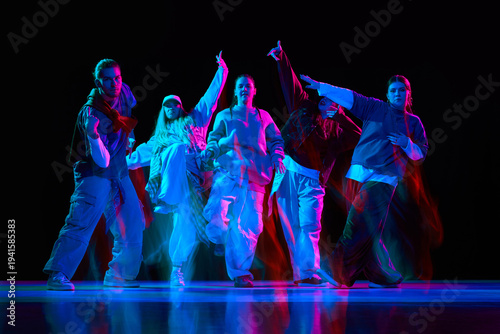 Foto Hip hop dancers performing synchronized street dance with neon lighting and moti