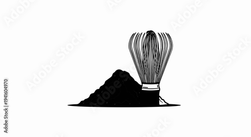 A bamboo whisk rests beside a mound of dark powder