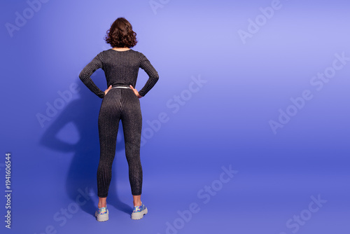 Canvastavla Young chic woman in glittery jumpsuit stands with hands on hips against purple s