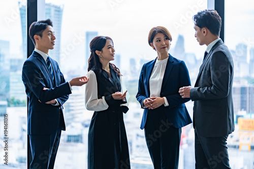 オフィスで会話する日本人ビジネスチームのミーティング風景
