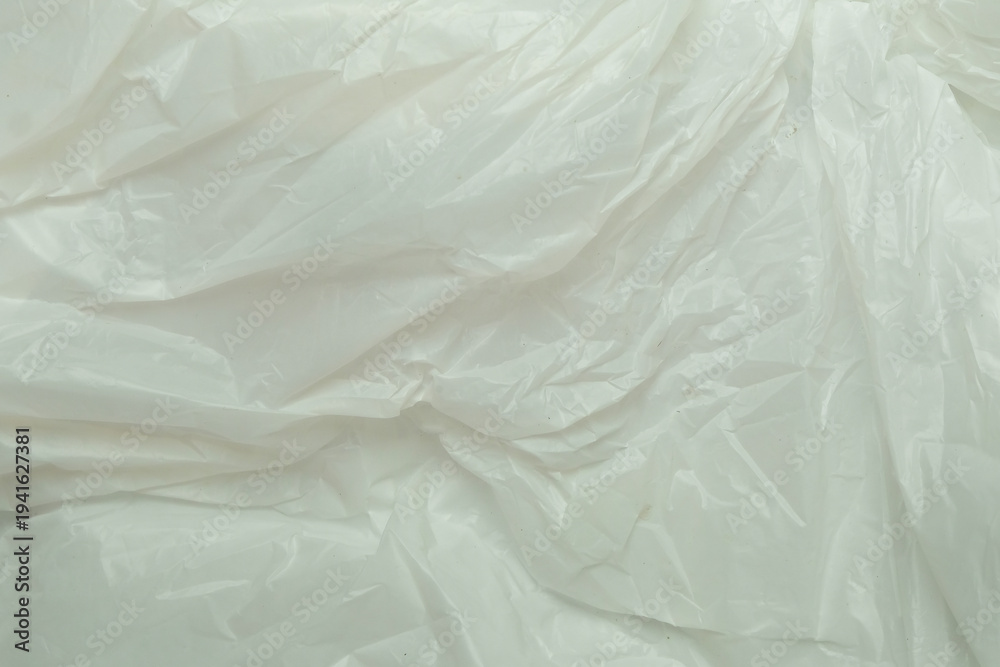 Fototapeta premium Close-up glossy wrinkled and crumpled white plastic surface texture background. Reflective plastic material with abstract folds. Clean industrial and packaging concept