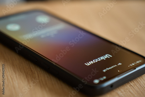 Foto Close up of smartphone lying on wooden table with unknown incoming call on screen