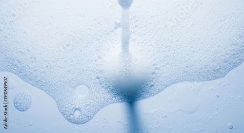 Bright blue-toned close-up of foam and water stream creating many delicate bubbles