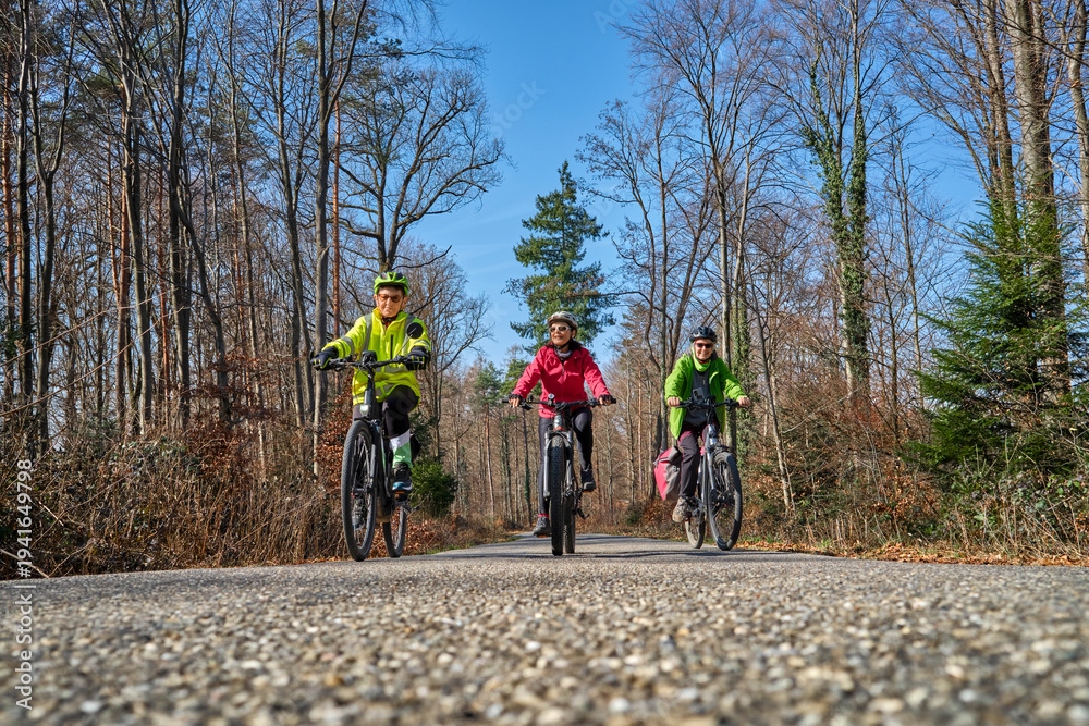 Fototapeta premium Group of active senior women enjoying a bicycle tour on a sunny spring day in the Swabian Forest, Germany. Friends cycling together through nature, promoting healthy lifestyle, recreation, and outdoor