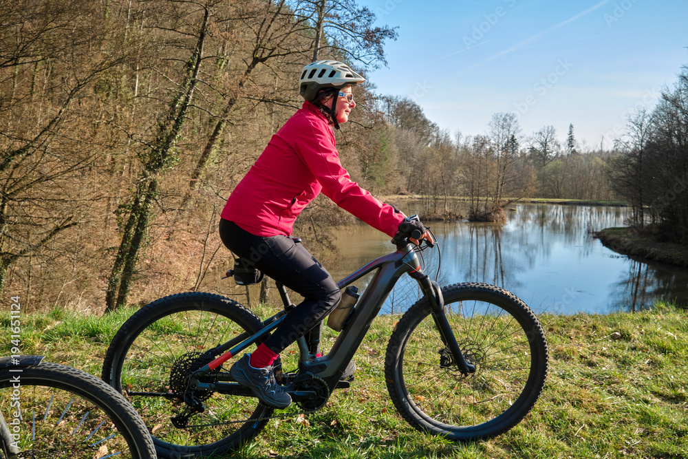Obraz premium active senior woman cycling with her electric mountain bike on a warm sunny spring day in the Swabian Forest, in Badeb.Woerttemberg, Germany