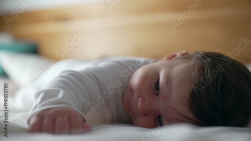 Fotografia Baby lying on stomach, playful expression, smiling while lifting head, early dev