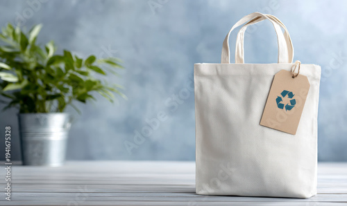 Ecological canvas tote bag with recycling tag and green plant in background