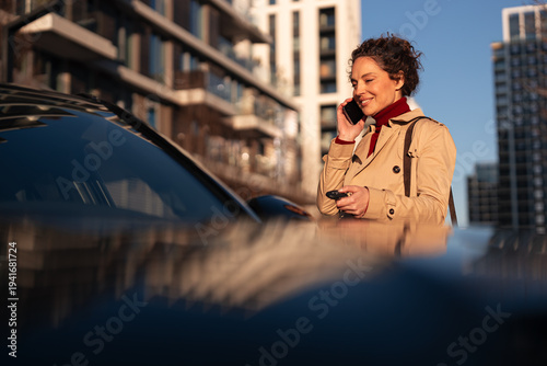 Woman making phone call unlocking car in city