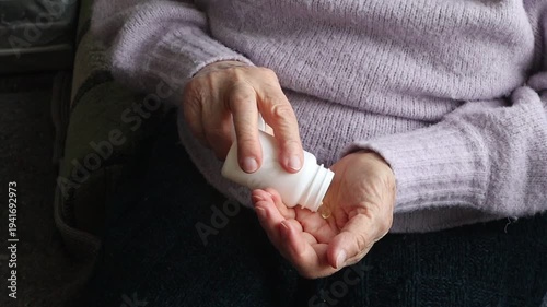 An elderly woman pours pills from a bottle
