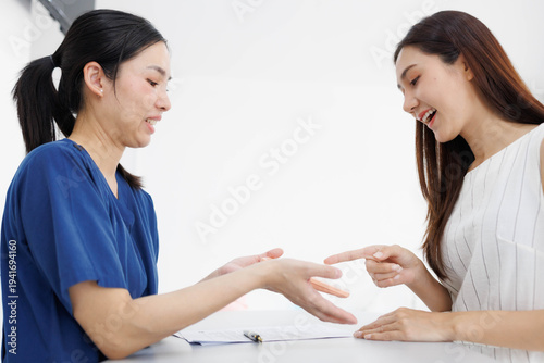 Professional aesthetician evaluates client's facial features. Client smiles, engaging in consultation with care. Soft lighting highlights calm, trusting interaction. Ideal for beauty, skincare
