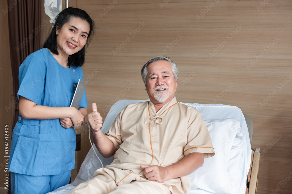 Obraz premium Asian nurse standing beside senior hospital patient giving thumbs up while sitting on hospital bed, healthcare support and positive recovery concept in medical environment