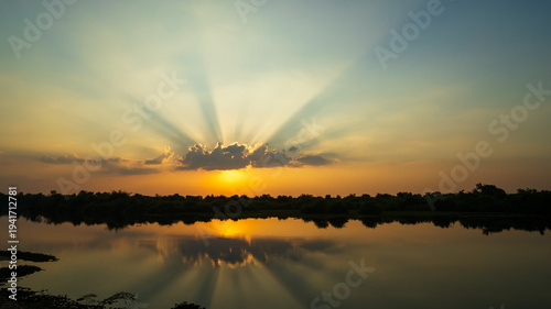 Golden Sunset Reflecting Over a Tranquil Lake with Radiant Sun Rays and a Serene Natural Landscape