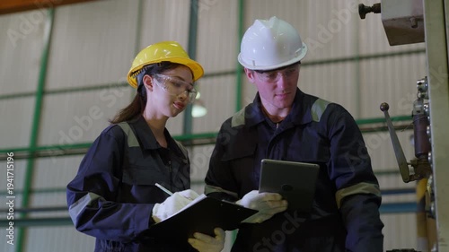 Diverse engineers factory workers holding clipboard and digital tablet checking production quality control. Technician team wearing safety equipment discussing project in industrial warehouse