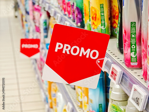 Red PROMO sale tag on a supermarket shelf, closeup of discount promotion sign with blurred grocery aisle and price labels, retail marketing strategy special offer concept, shopping savings banner