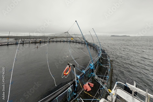 Large fish farm in the water with nets under cloudy sky as background