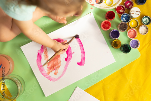 Child's hands drawing on white paper with colorful gouache, kid's education
