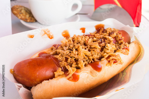 Tasty hot dog with grilled sausage, salt cucumber, mustard and crisps