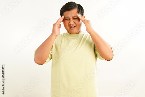 фотографія A close up portrait of an asian man in yellowish t shirt with a painful expressi