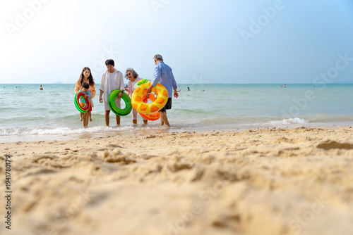 Multigenerational Asian family enjoying summer beach vacation, playing and relaxing together.