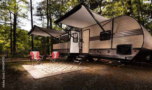 Camper trailer set up with awnings out at a shady campsite