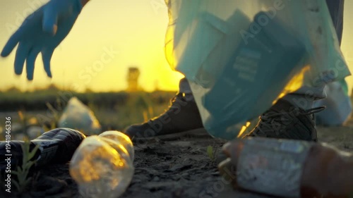 An environmental volunteer methodically segregates plastic bottles from glass trash during an evening conservation effort, promoting sustainability in a natural area