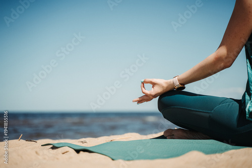 Foto Close-up of woman meditating on yoga mat at sandy beach, hands in mudra gesture