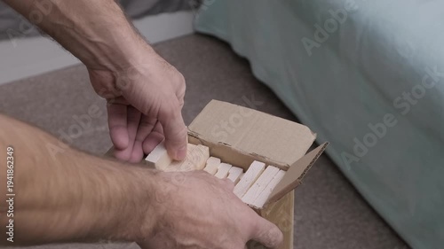man takes out wooden planks from cardboard box, slow motion
