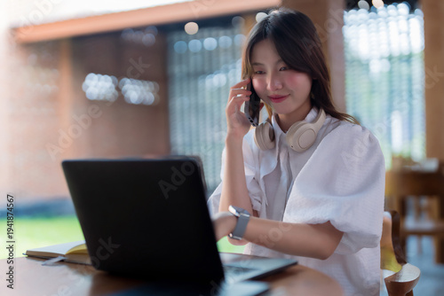 Asian adult woman using smartphone laptop working remotely cafe business communication online learning student digital nomad technology connectivity professional freelance remote worker