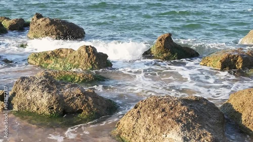 sea surf splashed among stones on coast, slow motion
