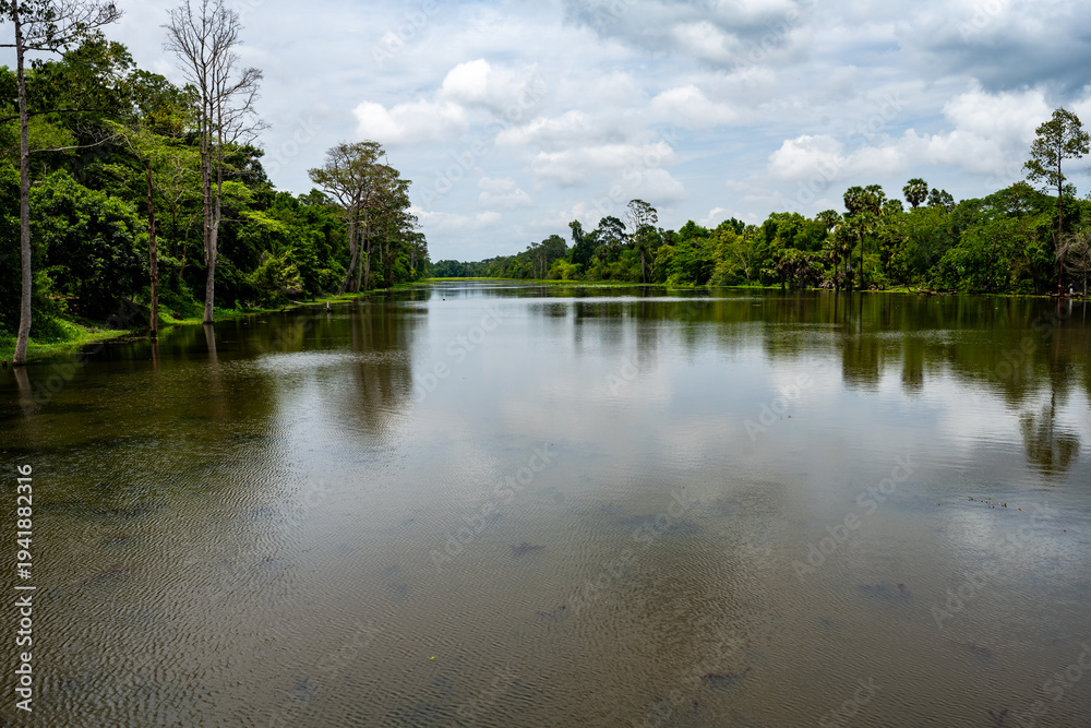 Obraz premium Calm reflective lake surrounded by tropical forest in Siem Reap