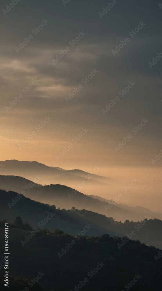 Fototapeta premium Mountain range with fog at sunset