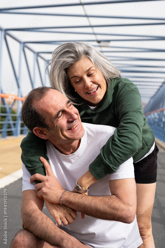 Naklejka premium Happy mature couple sharing an affectionate moment outdoors in sportswear