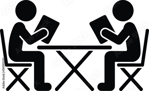 Two individuals engaged in a discussion over a table with books.