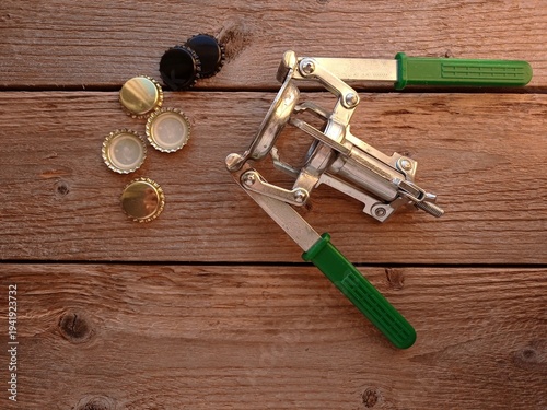 фотографія Close up of some crown corks and a manual crown capper on a wooden table