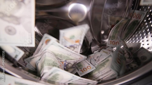 United States Dollar banknotes inside washing machine spinning in slow motion for money laundering and fraud concept.